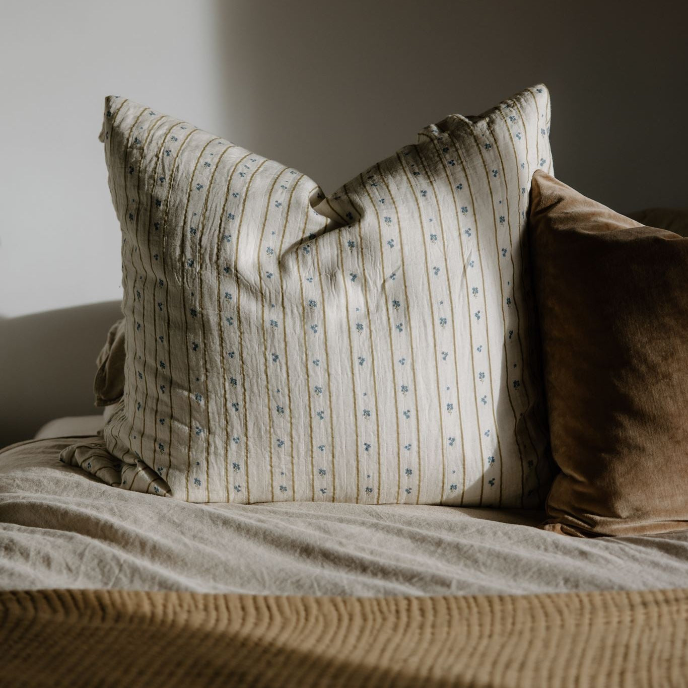 Striped pillow on a bed with a neutral background